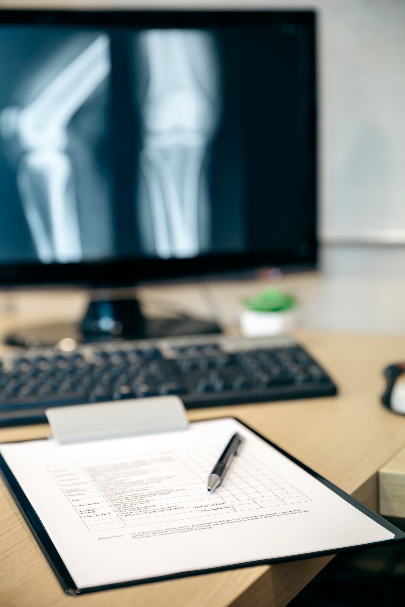 Close-up of medical report on table and x-ray image on computer screen